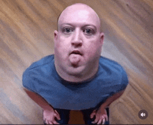 a bald man in a blue shirt making a funny face