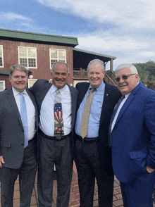 four men are posing for a picture with one wearing a tie with an american flag on it