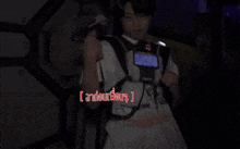 a man in a white shirt is holding a gun in a dark room with a foreign language written on the bottom