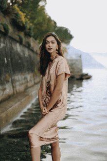 a woman in a satin dress is standing in the water