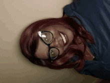 a woman with red hair and glasses is smiling