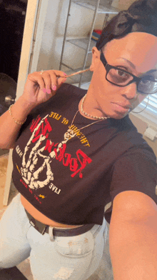 a woman wearing glasses and a crop top that says ' skeleton ' on it takes a selfie