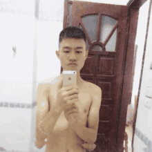 a shirtless man takes a picture of himself in a mirror