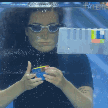 a woman wearing sunglasses is playing with a rubik 's cube in a pool with the word talent on the bottom