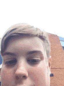 a close up of a boy 's face with a brick building in the background