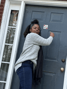 a woman is standing in front of a door that has a sticker on it that says ' i voted '