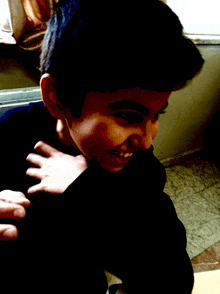 a boy in a black shirt is smiling with a hand on his shoulder