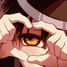 a close up of a person making a heart with their hands over their eyes .