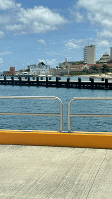 a fence along a body of water with a building in the background that says " welcome "