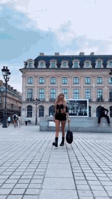 a woman walking in front of a large building with a sign that says ' l' amour ' on it