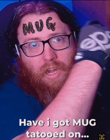 a man with glasses and a beard has the word mug tattooed on his face