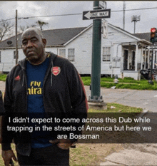 a man wearing a blue fly emirates shirt stands in front of a one way sign