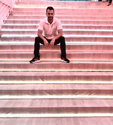 a man sits on a set of stairs that are lit up with pink lights