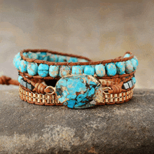 a bracelet with turquoise beads and a turquoise stone sits on a rock