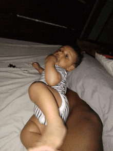 a baby is laying on a bed with a person holding it