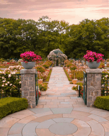 a garden with a circular walkway leading to a gazebo with pink flowers