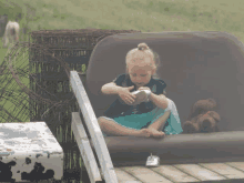 a little girl is sitting on a couch with a teddy bear