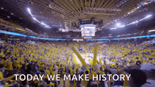 a crowd of people are watching a basketball game in a stadium with the words `` today we make history '' .