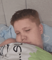 a young boy is sleeping under a blanket that says ' jesus '