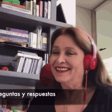 a woman wearing red beats headphones is smiling in front of a bookshelf with the words preguntas y respuestas below her