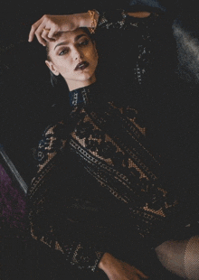 a woman in a black lace top is laying on a couch