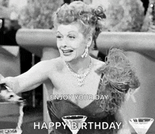 a black and white photo of a woman sitting at a table with two martini glasses and a happy birthday message .