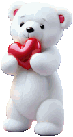 a white teddy bear is holding a red heart in its hands