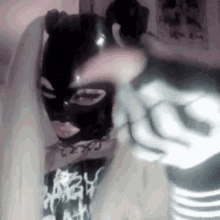 a woman wearing a black mask and a skeleton hand is holding a gun .