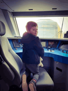 a little boy is sitting in the driver 's seat of a vehicle