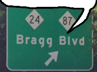 a green sign that says bragg blvd with an arrow pointing right