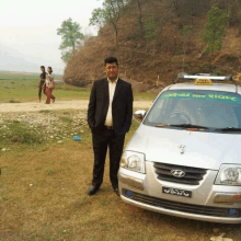 a man in a suit stands in front of a taxi cab