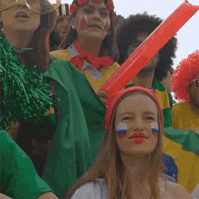 a woman with a russian flag painted on her face is standing in a crowd of people holding flags .