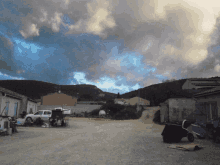 a white truck is parked in a dirt area with a cloudy sky in the background