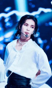 a man with long hair is wearing a white shirt and a pearl necklace