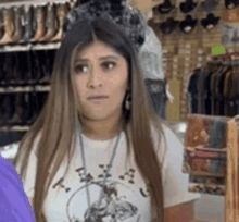 a woman in a white shirt is standing in front of a display of cowboy boots .