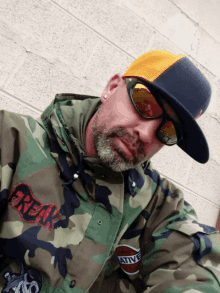 a man wearing a camo jacket and a hat with the word freak on it