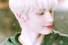 a close up of a person 's face with white hair and red lips wearing a green hoodie .