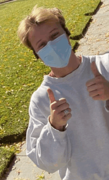 a young man wearing a face mask gives a thumbs up