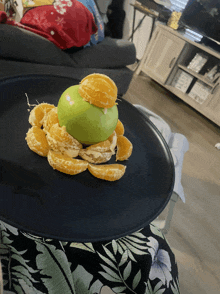 a black plate with sliced oranges and an apple on it