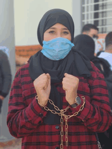 a woman wearing a face mask is chained to a chain around her neck