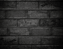 a black and white photo of a brick wall in a dark room