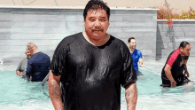 a man in a wet shirt stands in a pool with other men