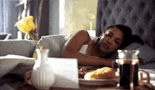 a woman is sleeping on a bed next to a table with a plate of food on it .