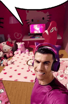 a man wearing headphones and a hello kitty headband smiles in a pink room