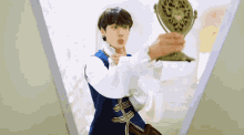 a man in a blue and white outfit holds a mirror