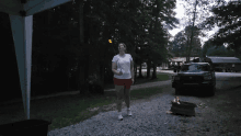 a woman walking down a gravel road with a torch