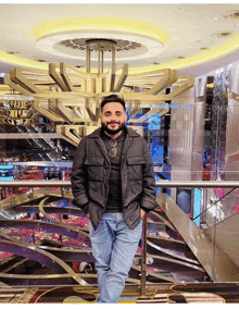 a man in a black jacket stands in front of a large chandelier that says ' ritz ' on it