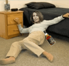 a woman is laying on the floor with a bottle of whiskey in her hand