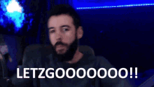 a man with a beard is sitting in front of a microphone with the words letzgo00000 written below him