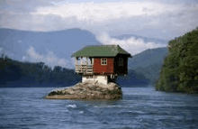 a small house is sitting on top of a rock in the middle of a river .